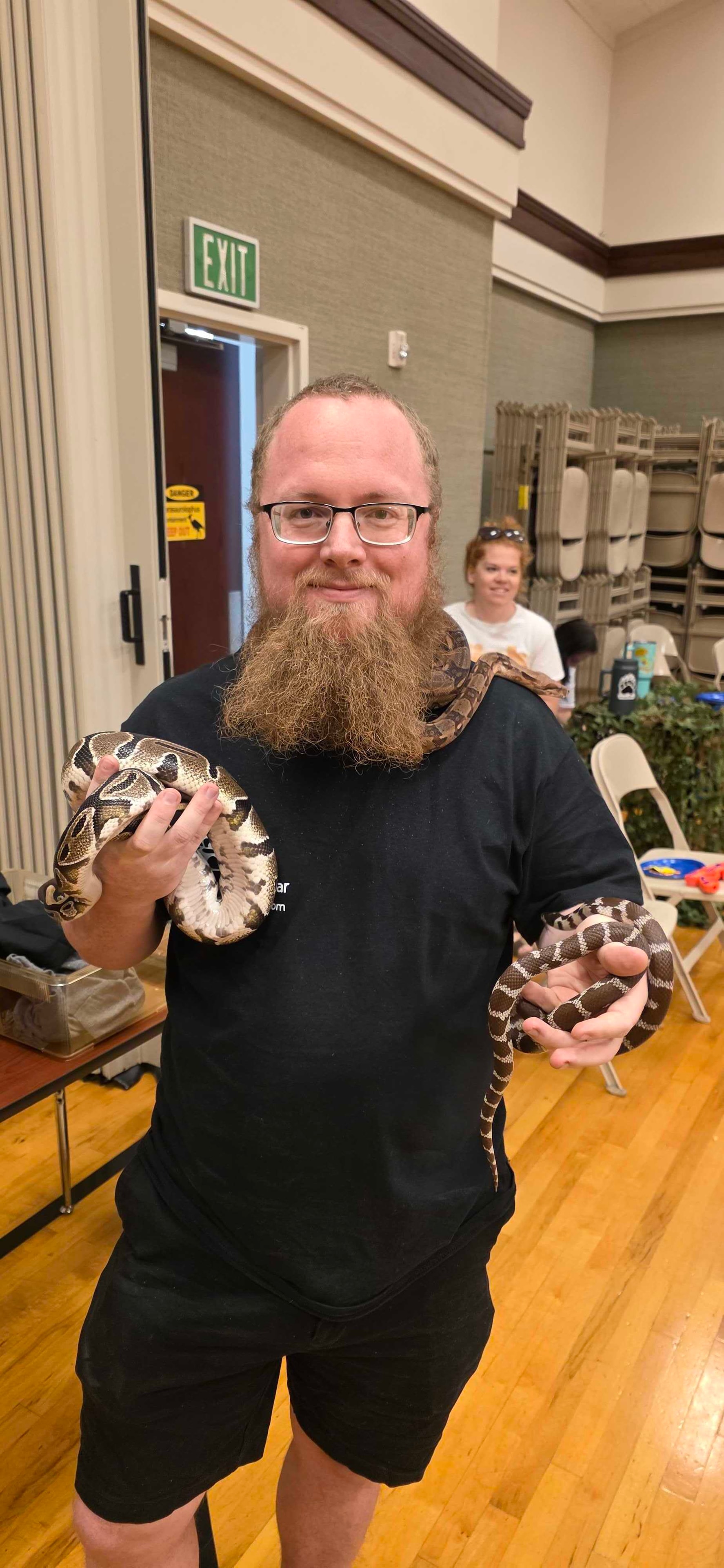 Host holding two snakes at a community event